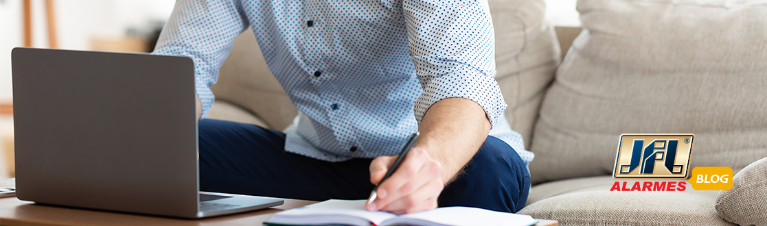 Homem de camisa social trabalhando em um notebook em uma mesa de centro.