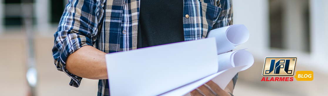 Homem segurando um projeto de alarme desenhado em um grande papel