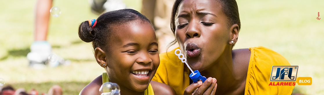 Mãe e filha negras brincando de bolinha de sabão