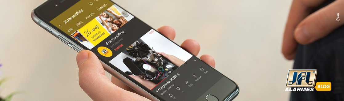 Foto focada no celular que está com o canal de youtube da JFL Alarmes na tela